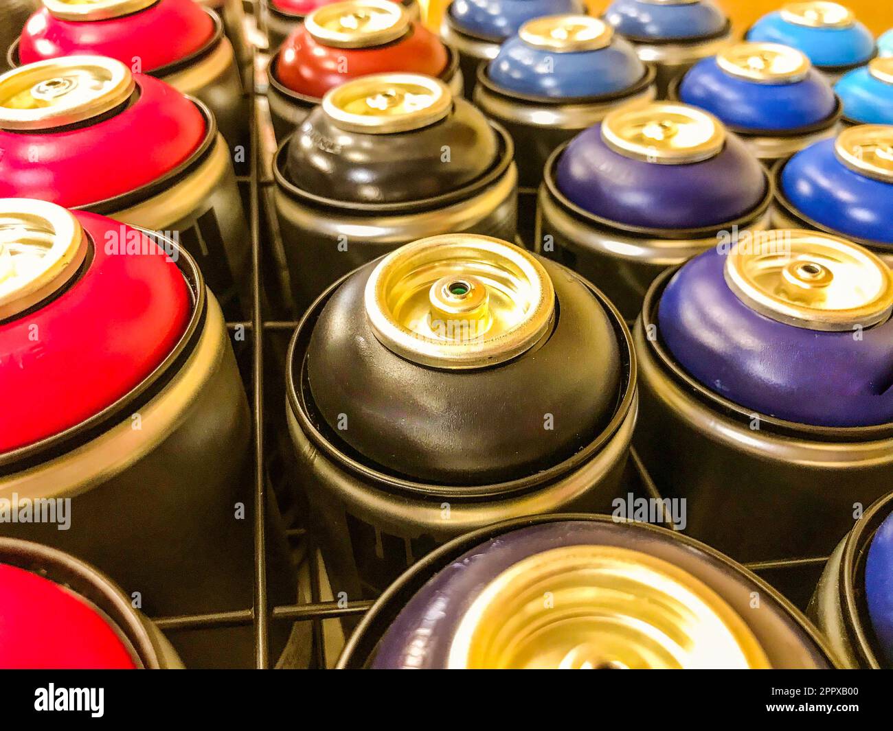 spray cans of paint are on display behind a metal mesh. paint sprayers