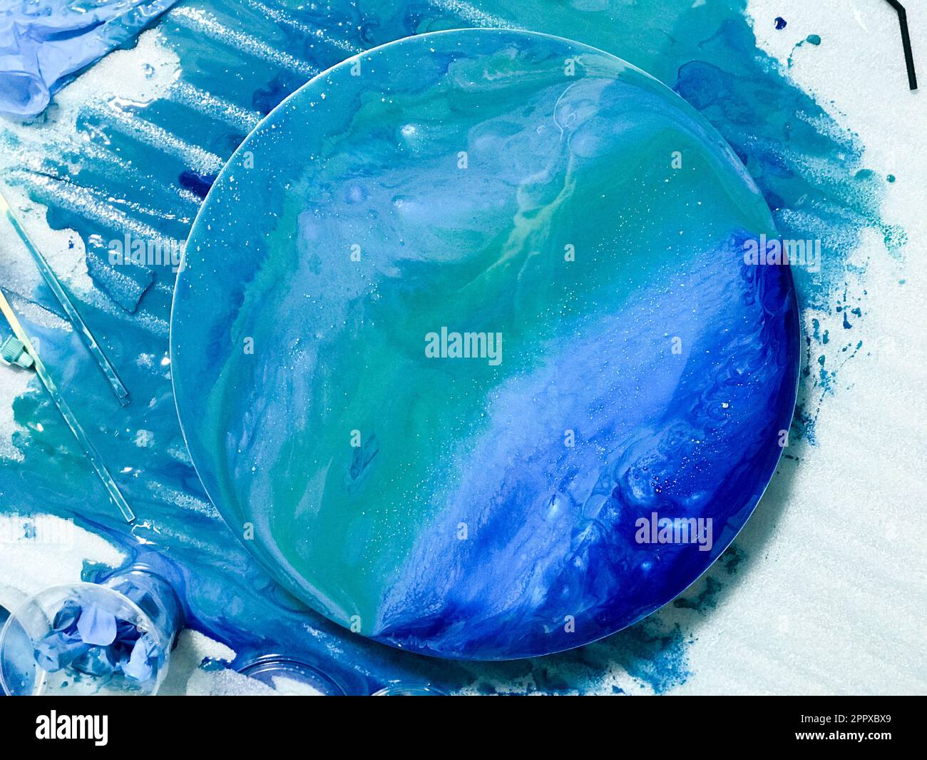 The process of creating a home-made trendy abstract modern pattern painted  with a brush of acrylic blue multi-colored resin on a round wooden board  14161668 Stock Photo at Vecteezy