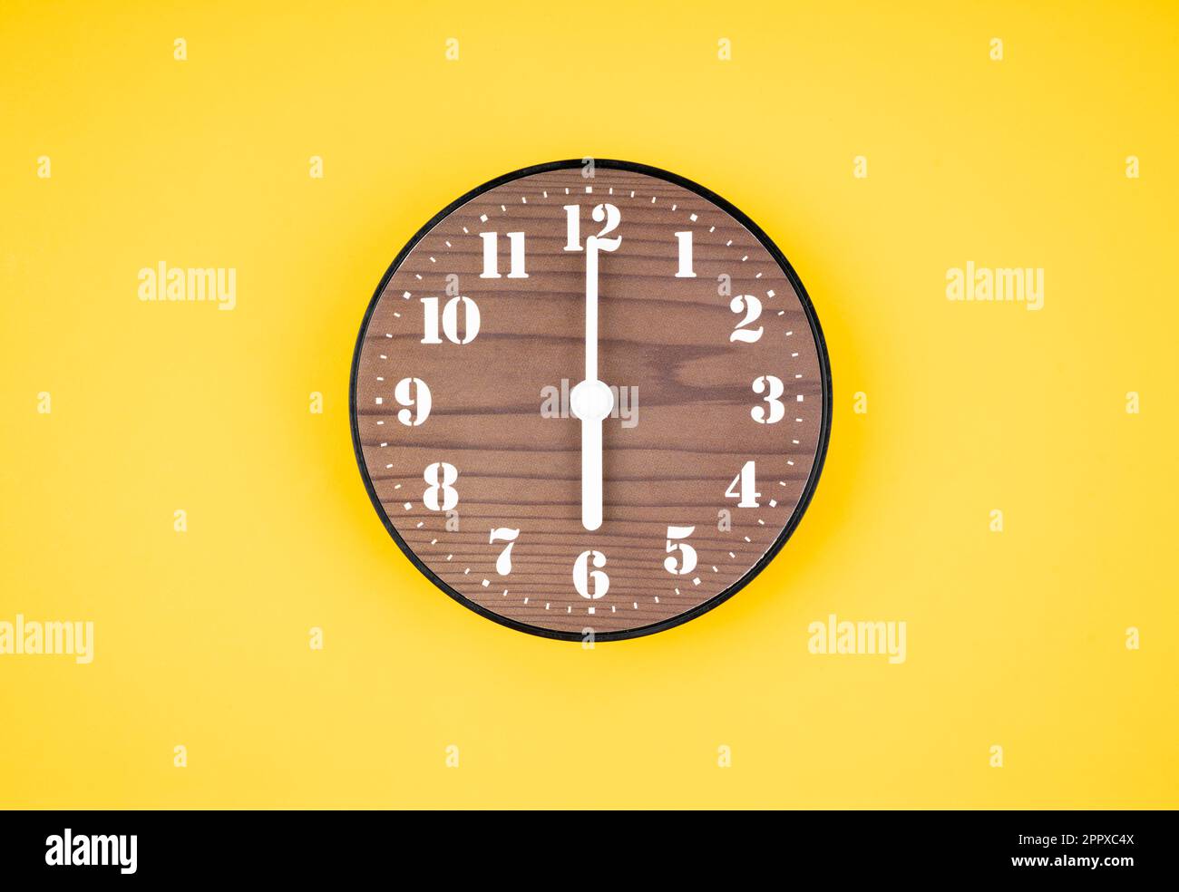 Retro wooden clock at 6 O' clock on yellow color background Stock Photo