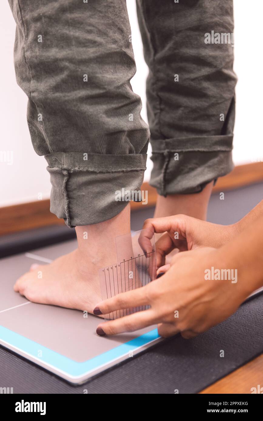Unrecognizable podiatrist measuring foot of patient while examining