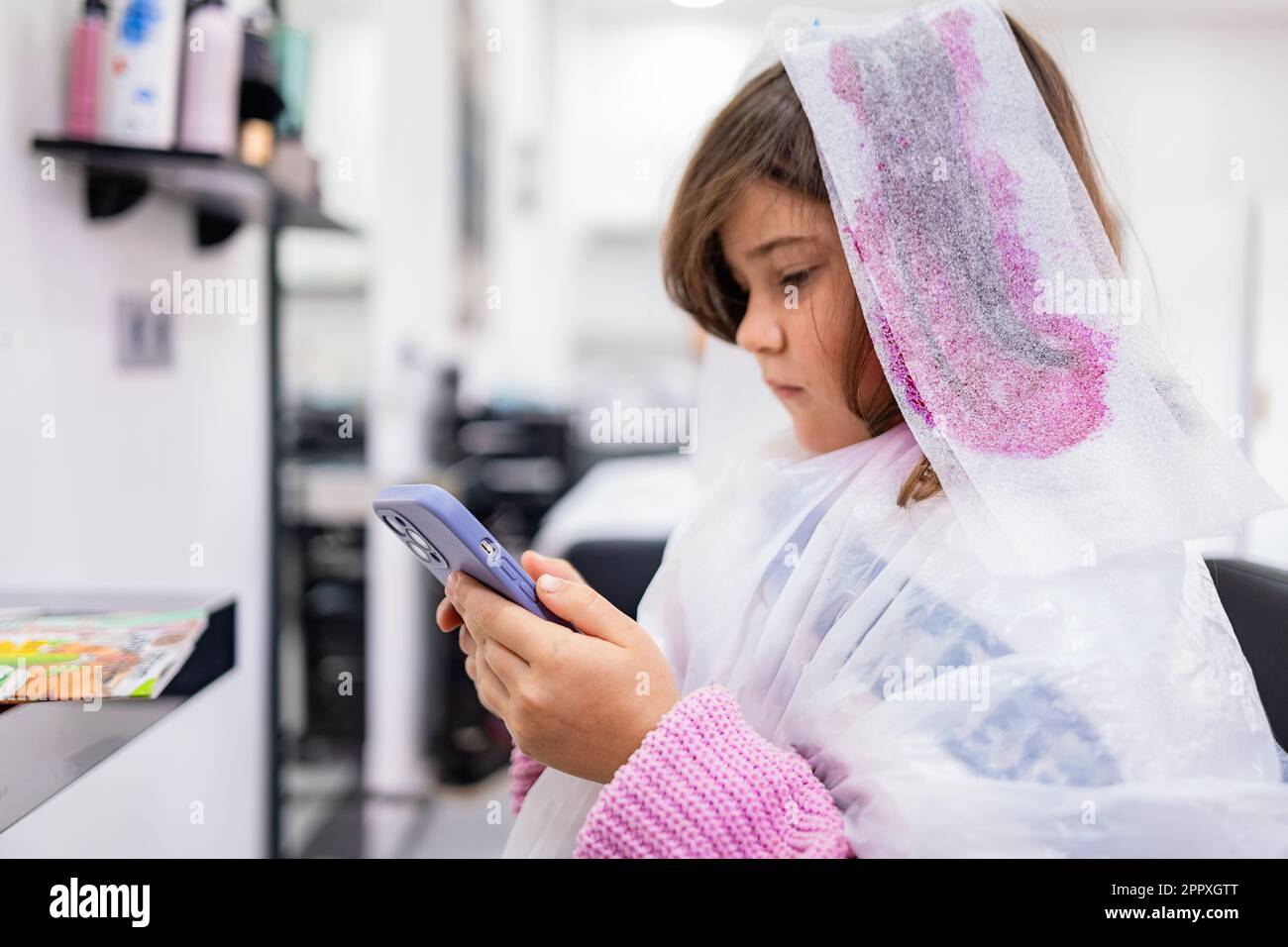 Side view of preteen girl looking at screen of mobile phone in hands ...