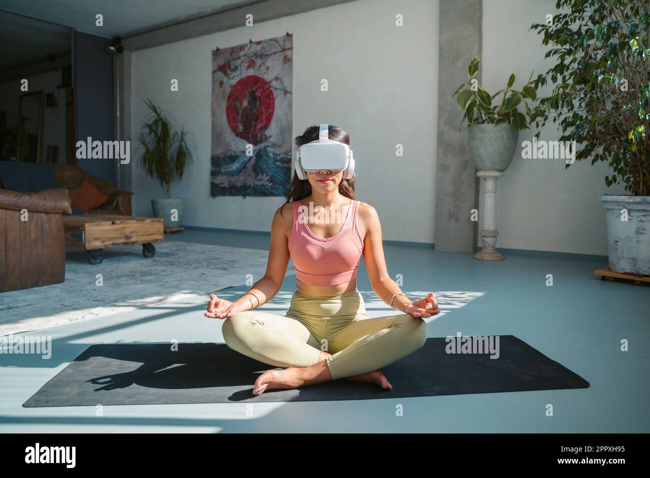 Full body of barefoot meditating female athlete in lotus pose sitting on mat  while exploring virtual world with VR goggles during yoga session Stock  Photo - Alamy
