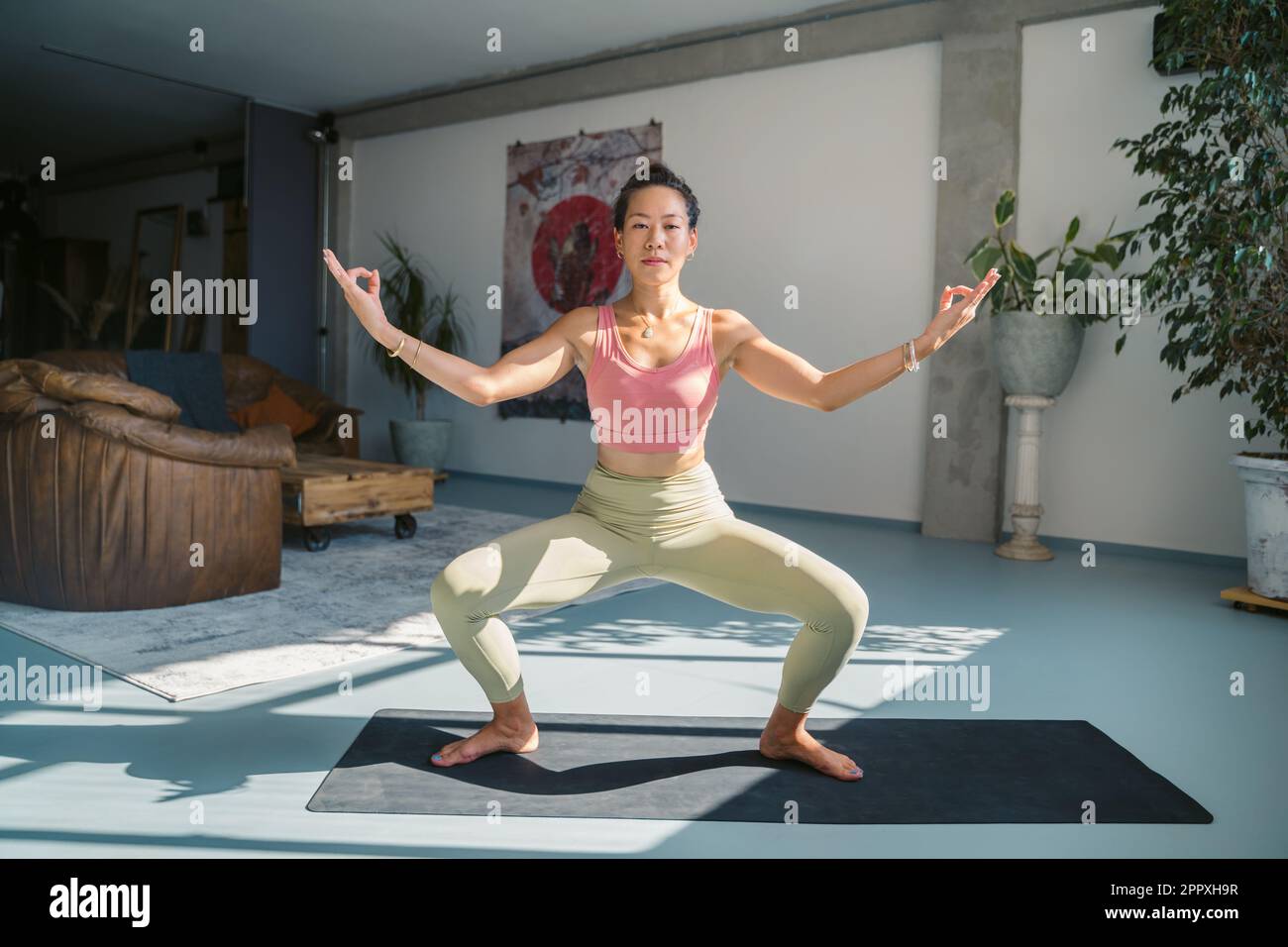 Full body of concentrated young Asian female in activewear doing Gyan