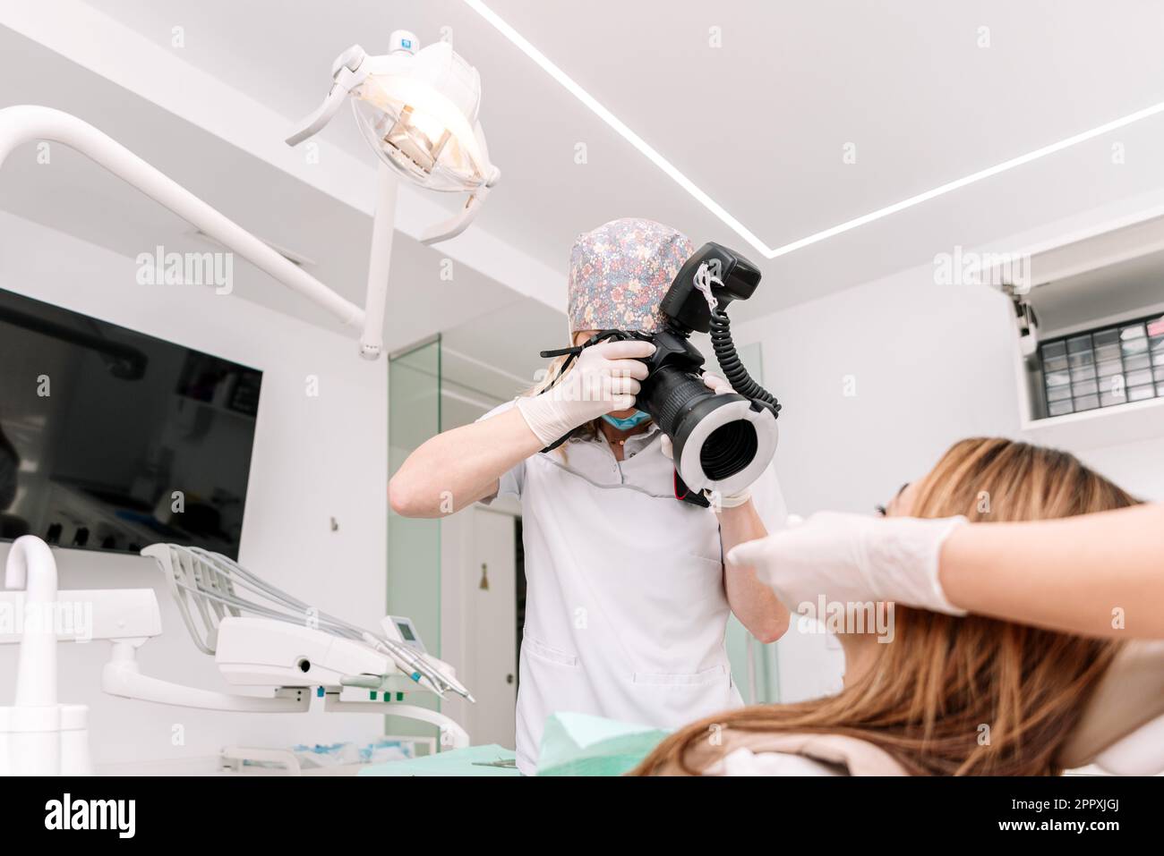 Female dental nurse keeping mouth prop while dentist shooting teeth of