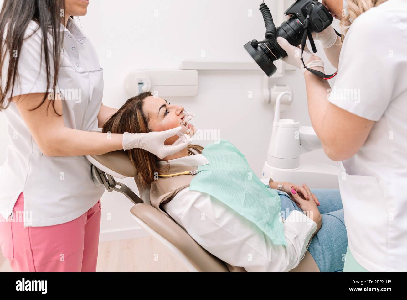 Female dental nurse keeping mouth prop while dentist shooting teeth of