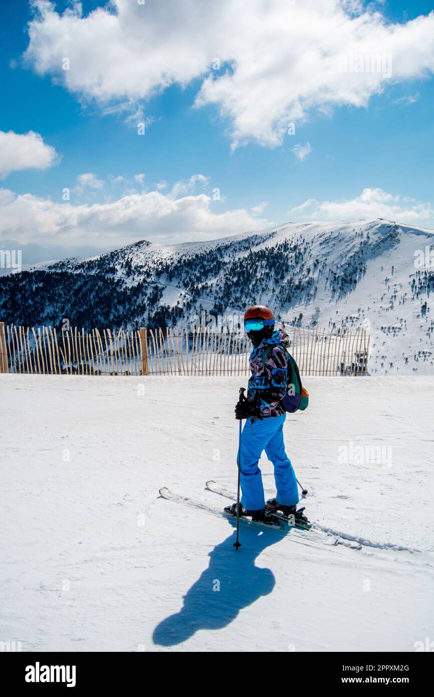 Full body side view of unrecognizable skier in warm ski suit and with skiing equipment standing on snowy slope with skiing poles Stock Photo Alamy