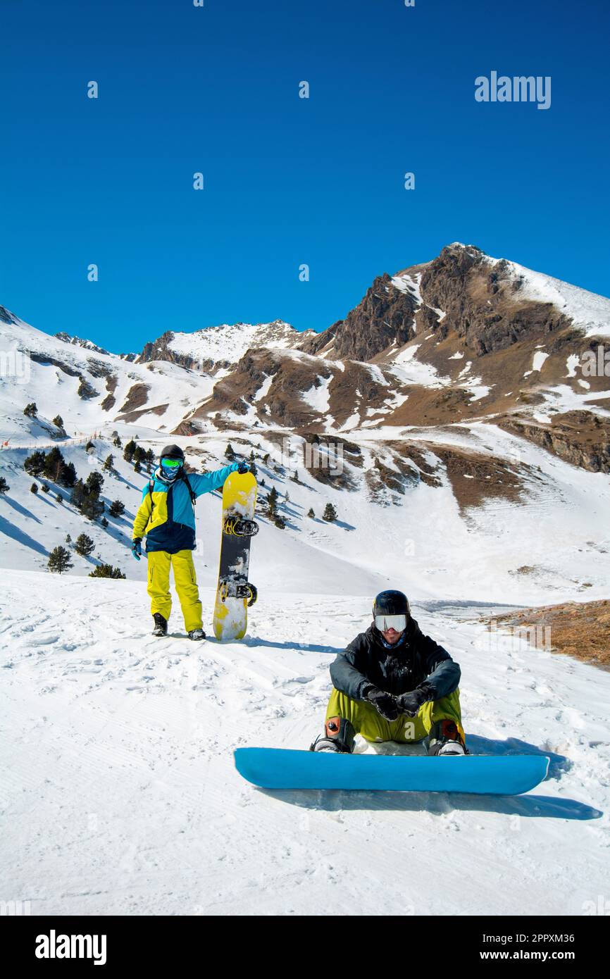 Anonymous snowboarders in warm ski suit and with snowboards looking at camera while spending winter holidays on snowy mountains Stock Photo