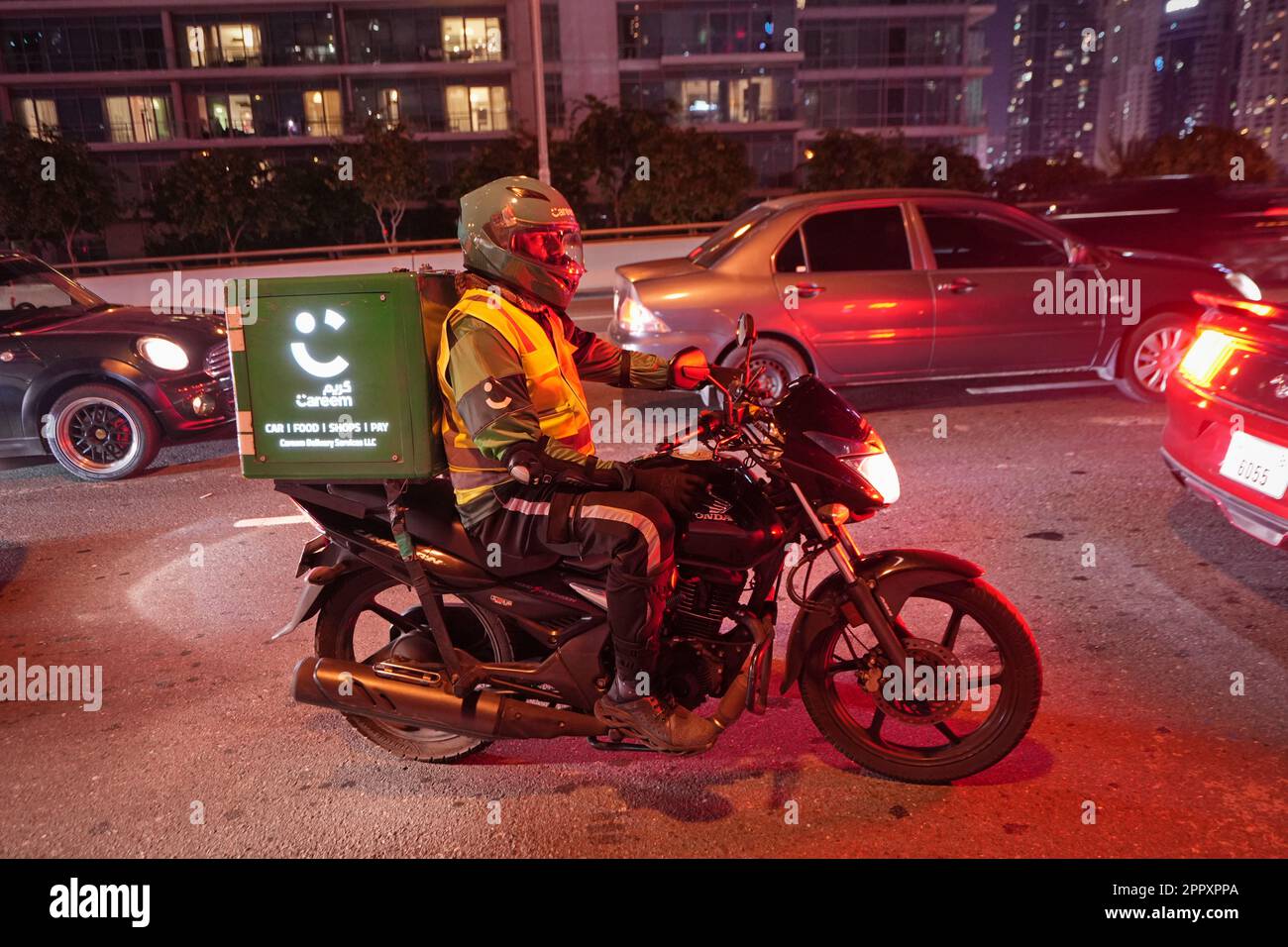 Motorcycle food delivery workers at work in the street. Dubai, United Arab Emirates - April 2023 Stock Photo