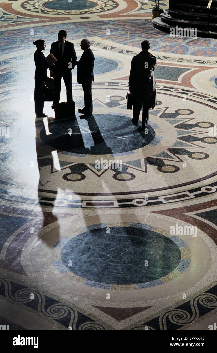 A group of Business executives meeting while standing on an ornate vintage lobby floor Stock Photo