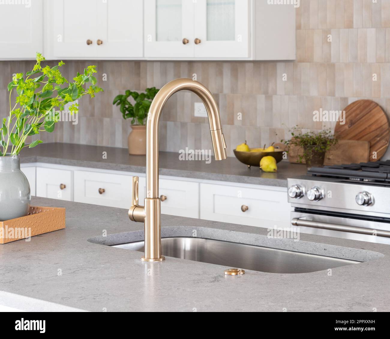 A kitchen faucet detail with a grey stone countertop island, gold