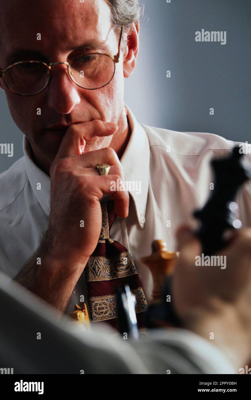 Caucasian business executive contemplating a strategic move in the game of chess Stock Photo