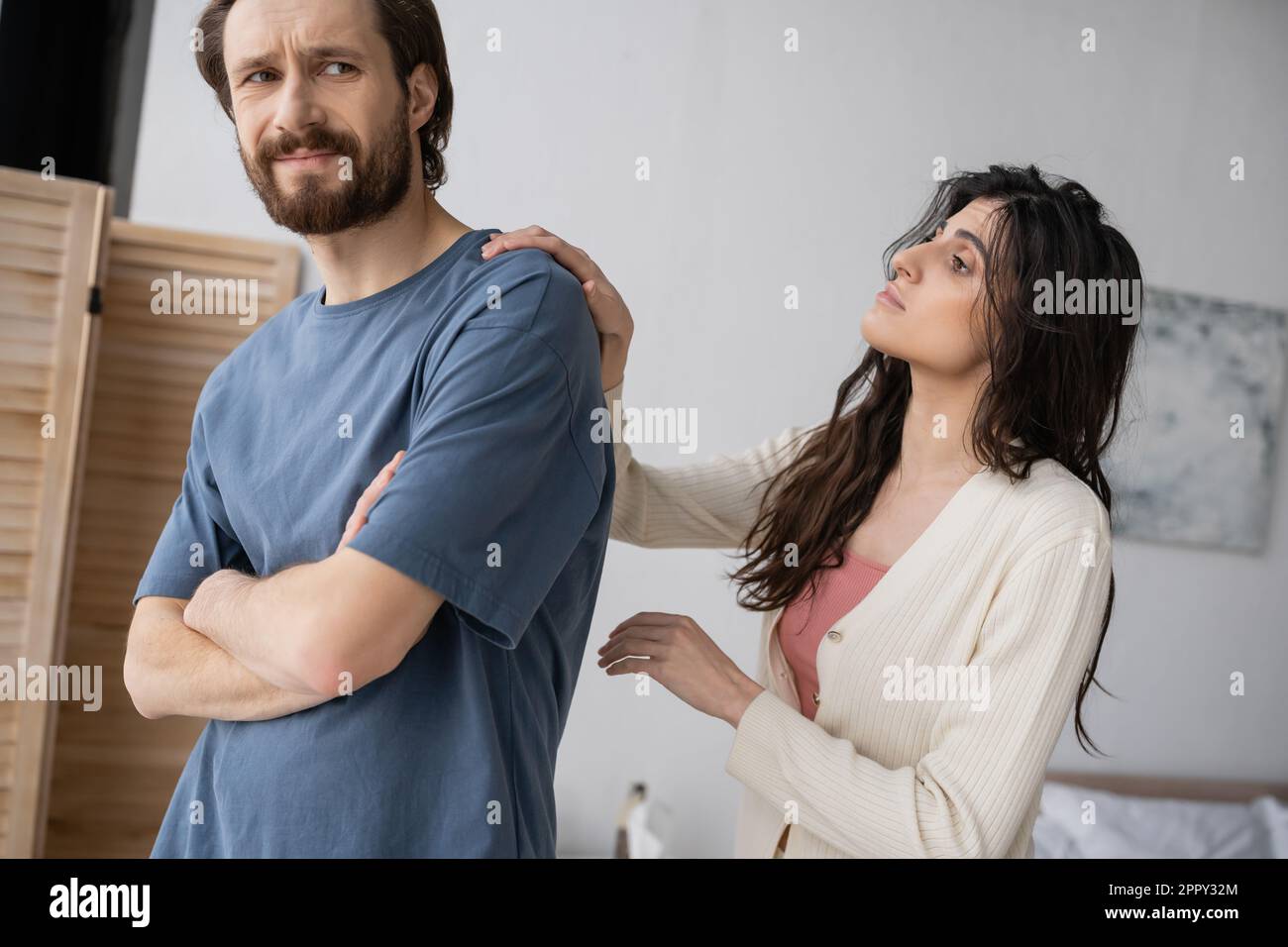 Brunette woman calming down offended boyfriend with crossed arms at home,stock image Stock Photo