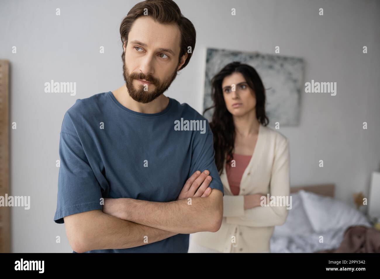 Offended man crossing arms near blurred girlfriend in bedroom,stock image Stock Photo