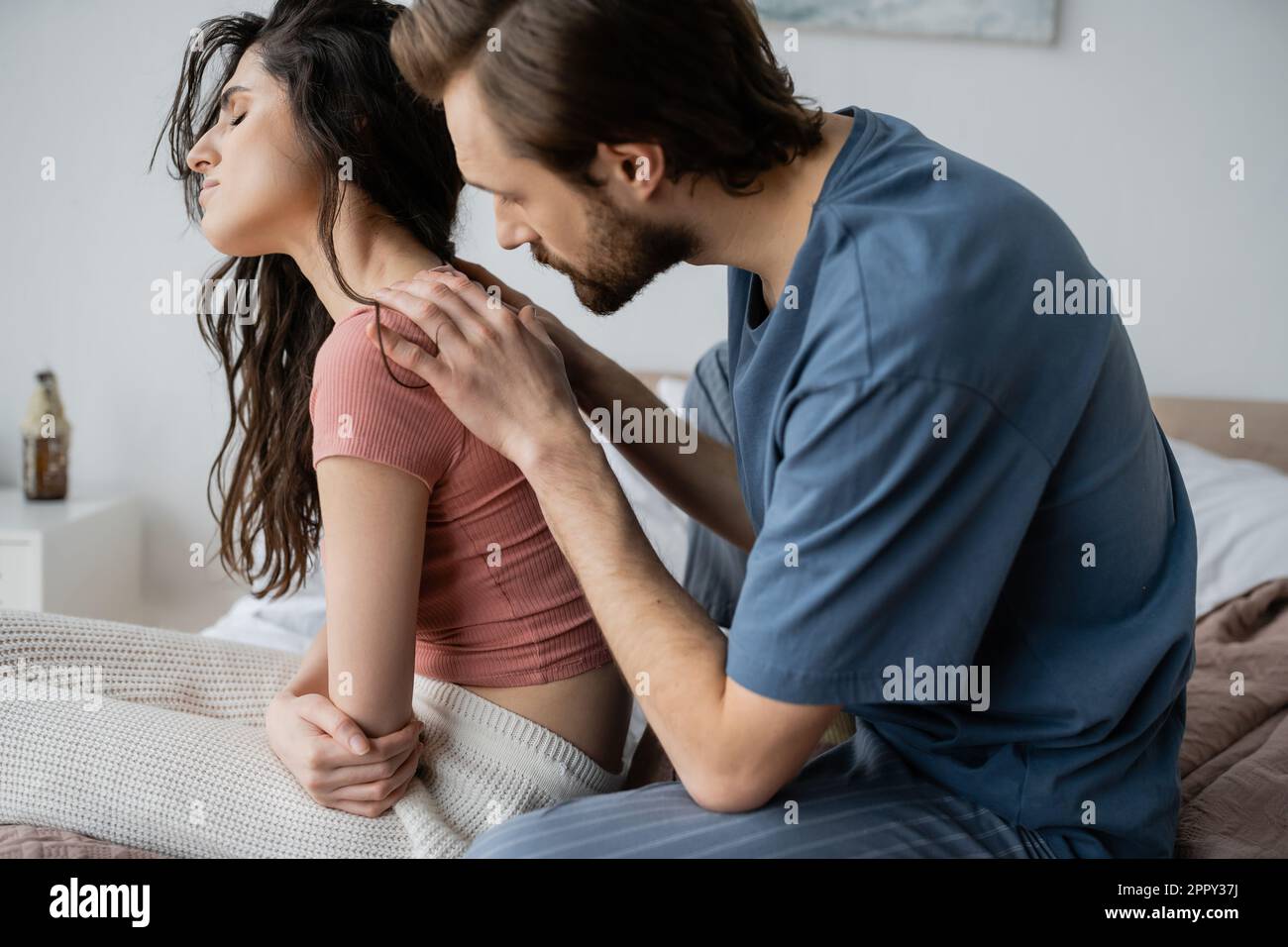 Man in pajama calming down sad girlfriend on bed at home,stock image Stock Photo