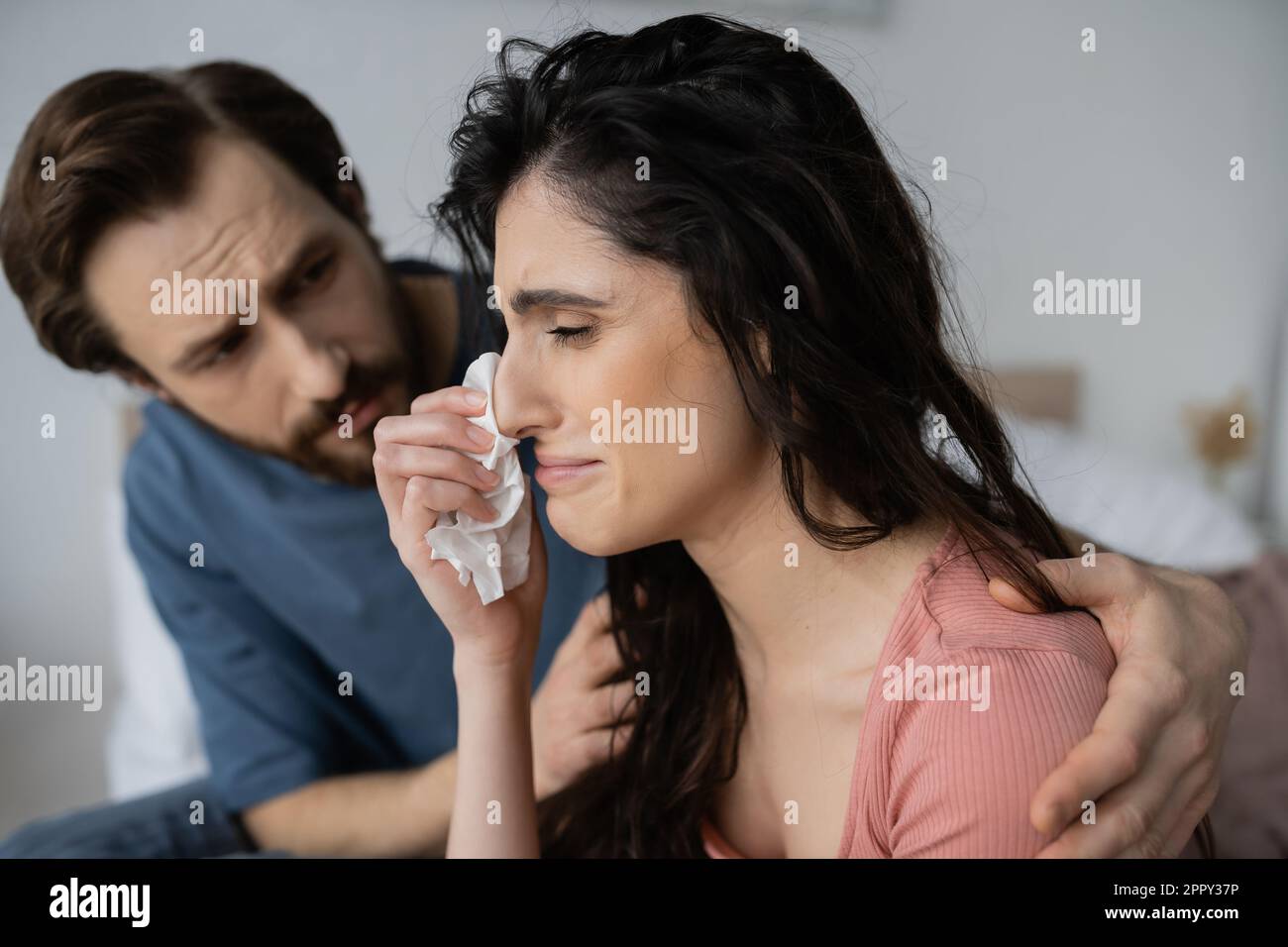 Displeased woman crying near caring blurred boyfriend at home,stock image Stock Photo