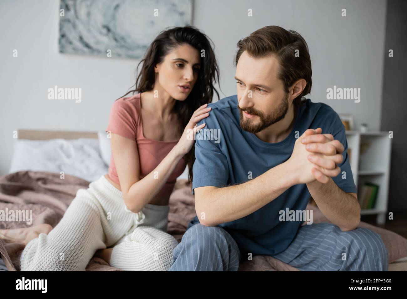 Brunette woman calming down boyfriend with clenched hands in bedroom,stock image Stock Photo
