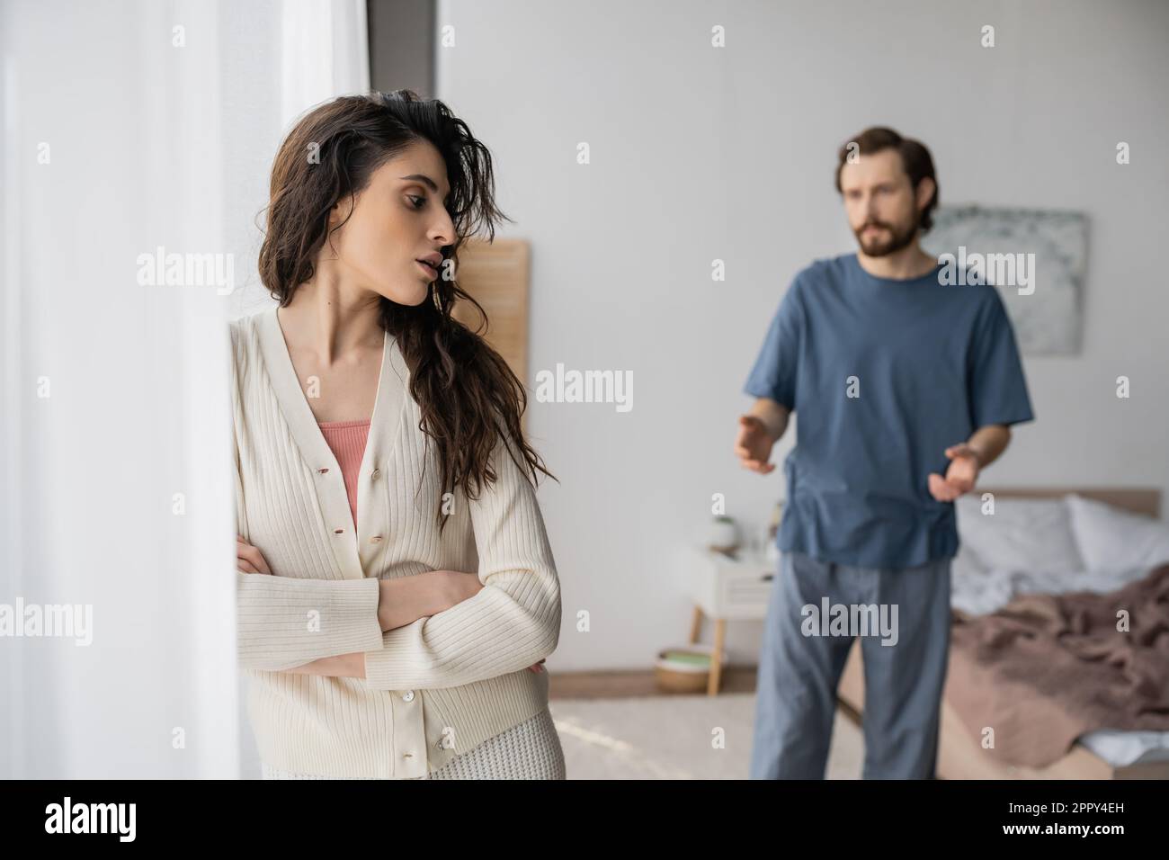 Displeased woman crossing arms near blurred boyfriend quarrelling at home,stock image Stock Photo