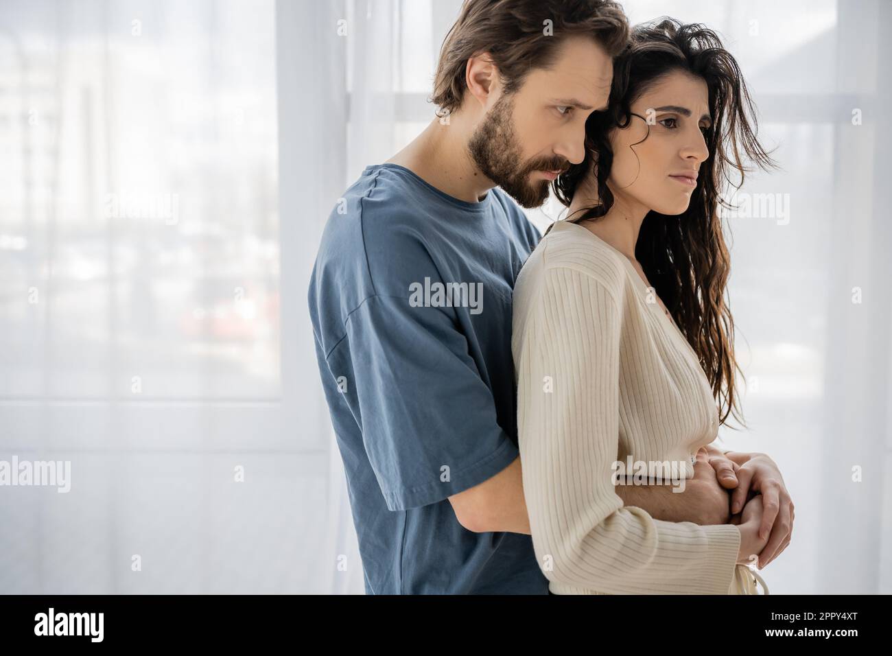 Caring bearded man embracing sad girlfriend at home,stock image Stock Photo