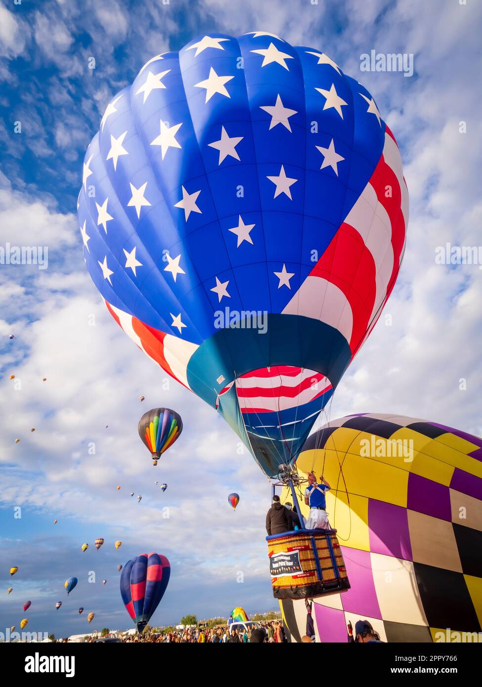 Stars and Strips hot air balloon lifting off into sky with a few people