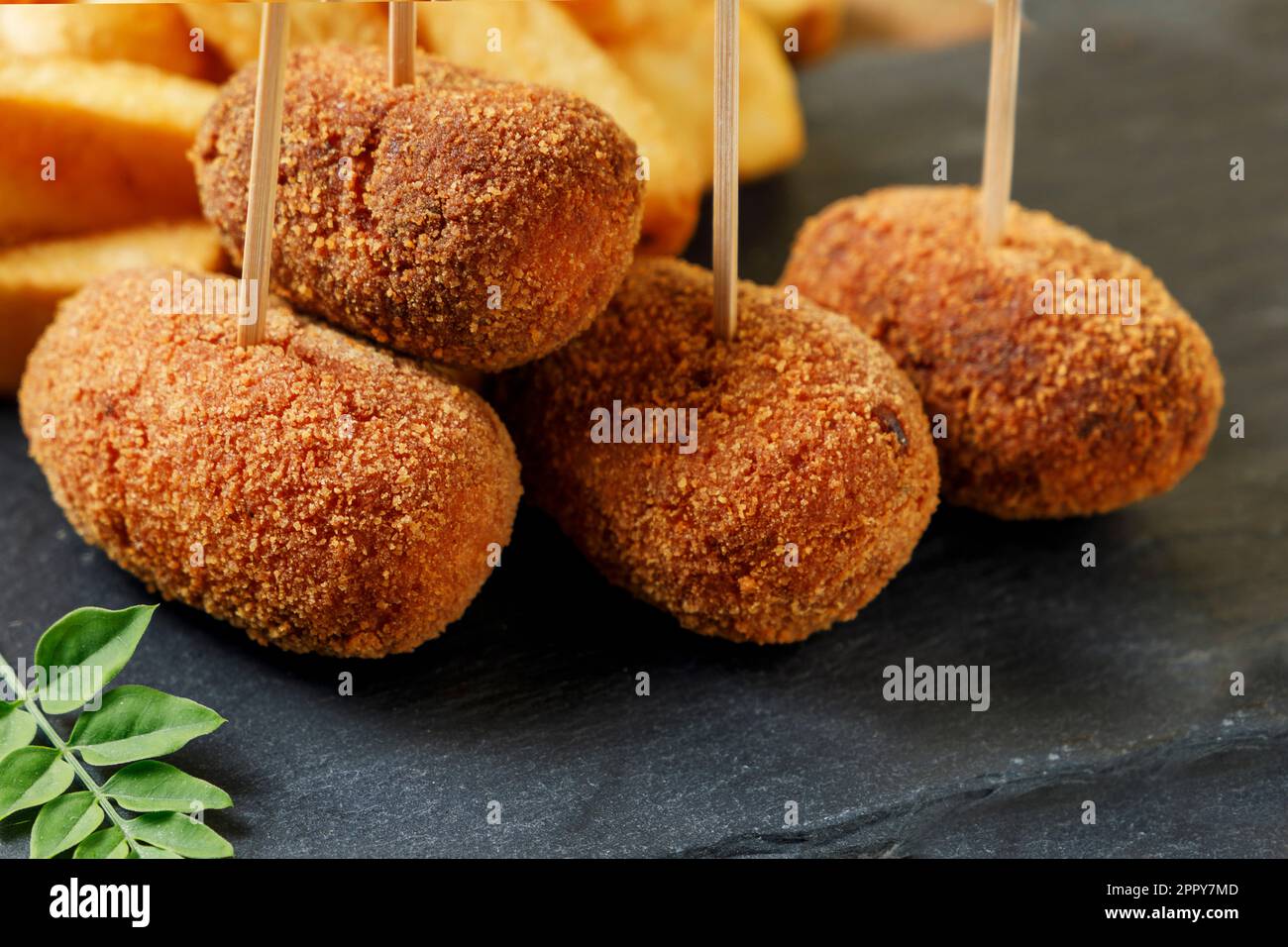 Close up of snack of ham croquettes and chips on a black stone. Stock Photo