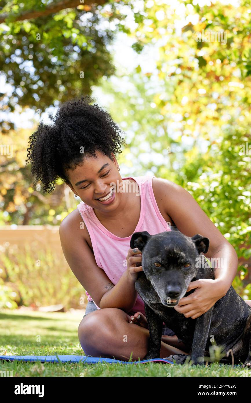 A multi-ethnic woman and her happy dog, giving attention in the park pet owner Stock Photo
