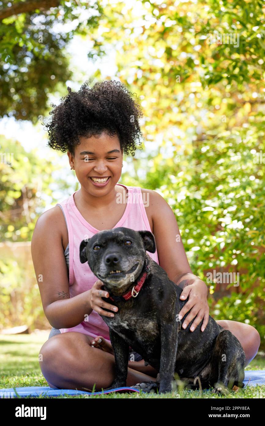 A multi-ethnic woman and her happy dog, giving attention in the park pet owner Stock Photo