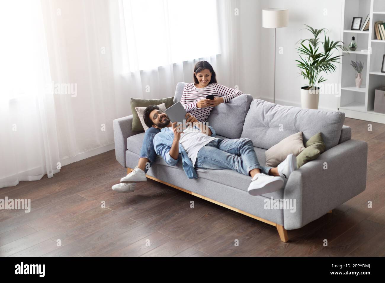 High angle view relaxed eastern lovers using gadgets at home Stock Photo