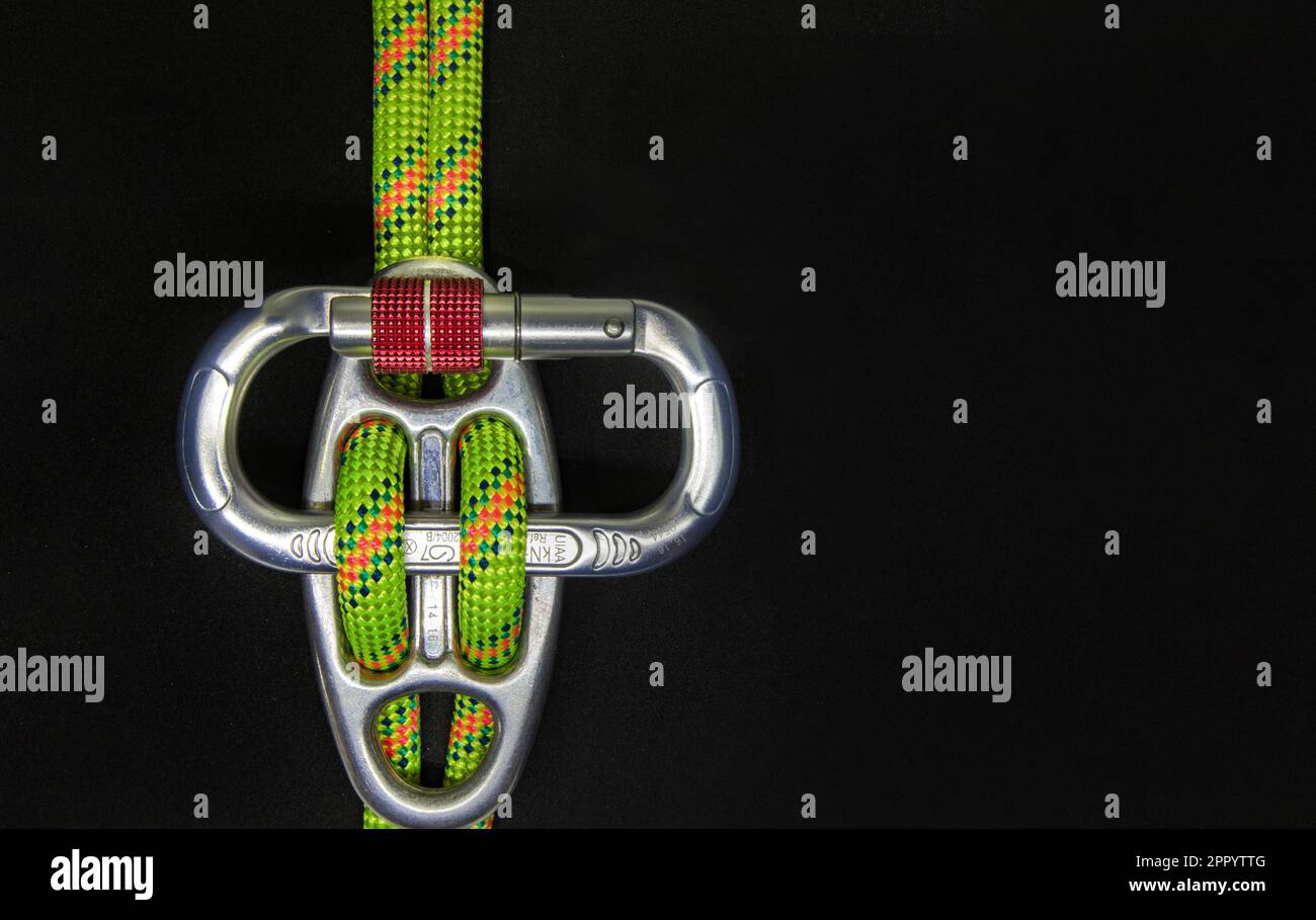 Discensore piastrina Gigi con moschettone ovale e sfondo nero scuro  in corda doppia verde fluo - strumento di arrampicata e discesa in sicurezza Stock Photo