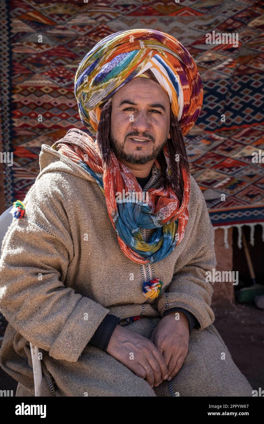 Portrait of a craftsman dressed in a colorful typical costume, sitting in front of his souvenir shop near the Kasbah of Telouet. Stock Photo