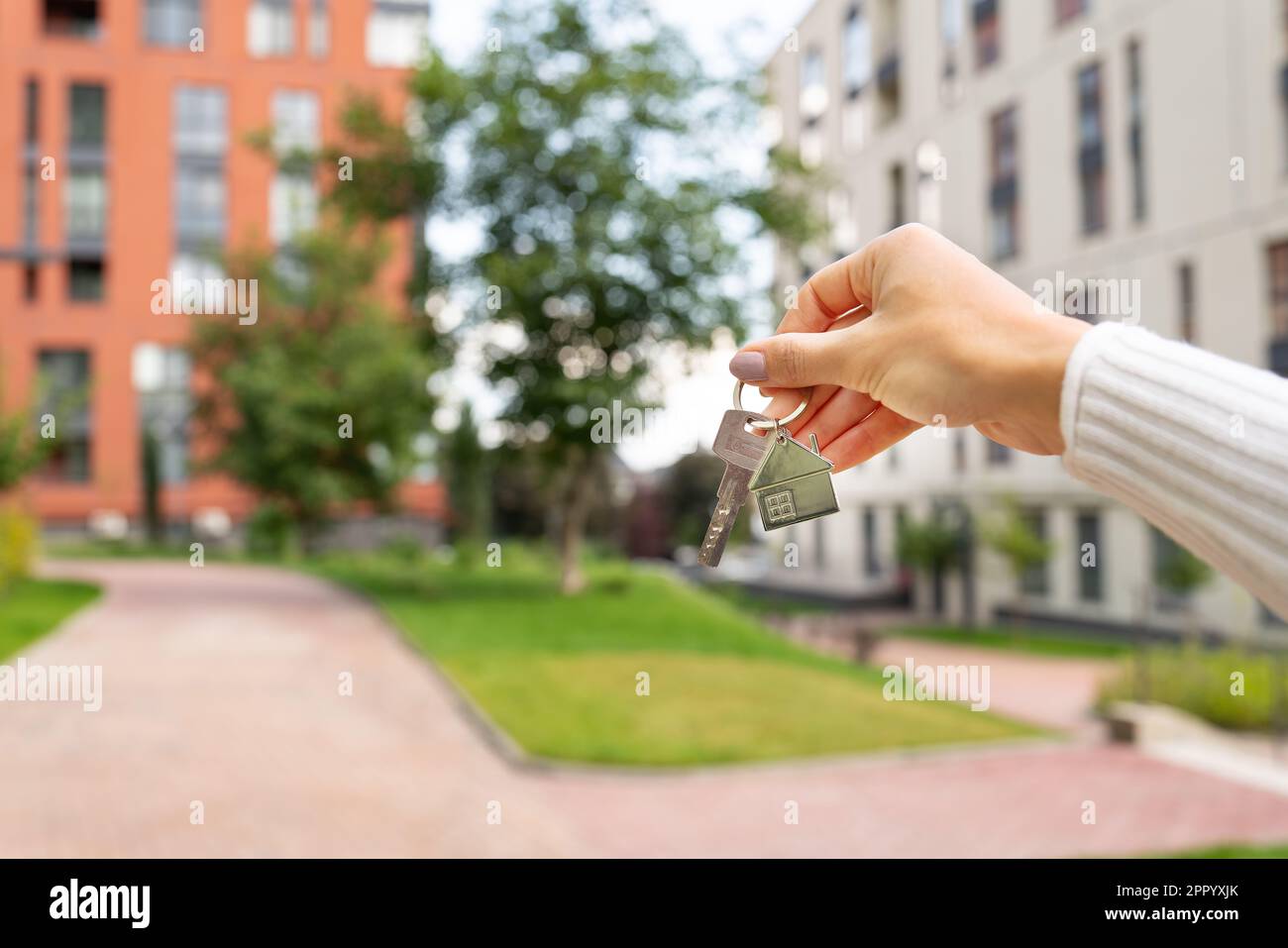 Hand holding keys on the background of a new building, construction