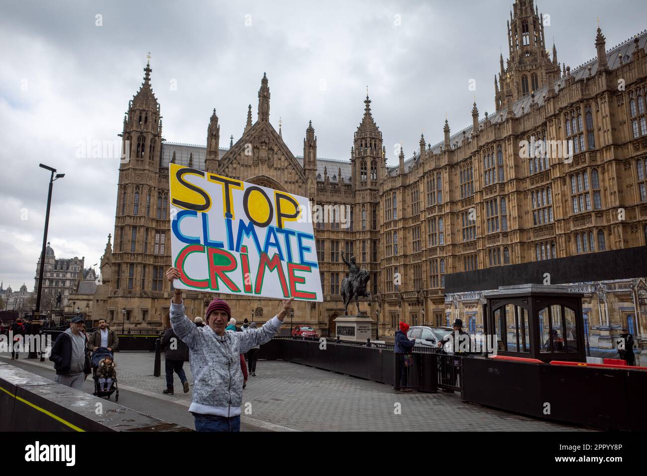 Extinction Rebellion protest, Friday 21st April 2023. Activist holds up large 'Stop Climate Crime' placard outside Palace of Westminster. XR London. Stock Photo