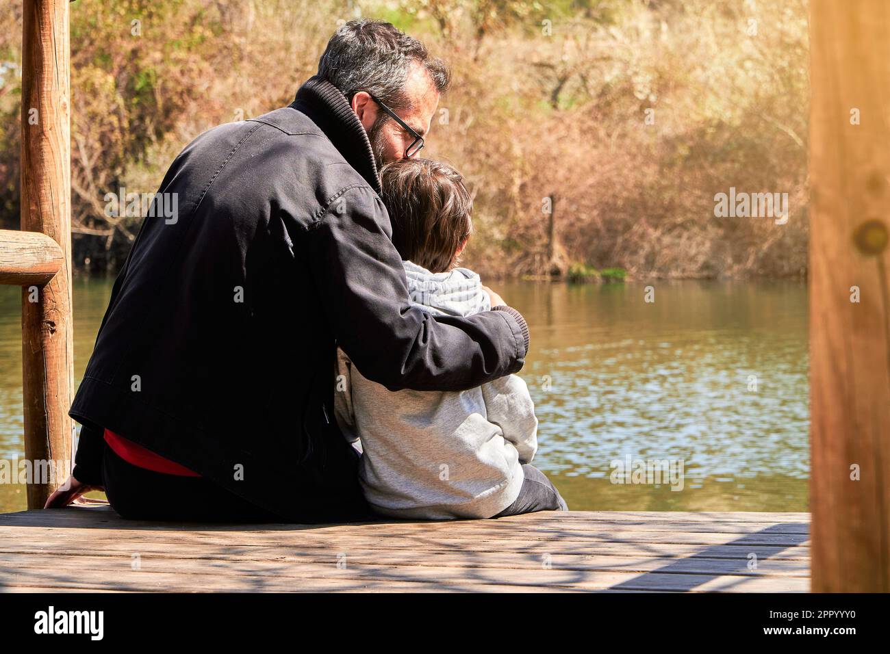 Father kissing and hugging his son while spending the day together in a sustainable lifestyle in the nature Stock Photo
