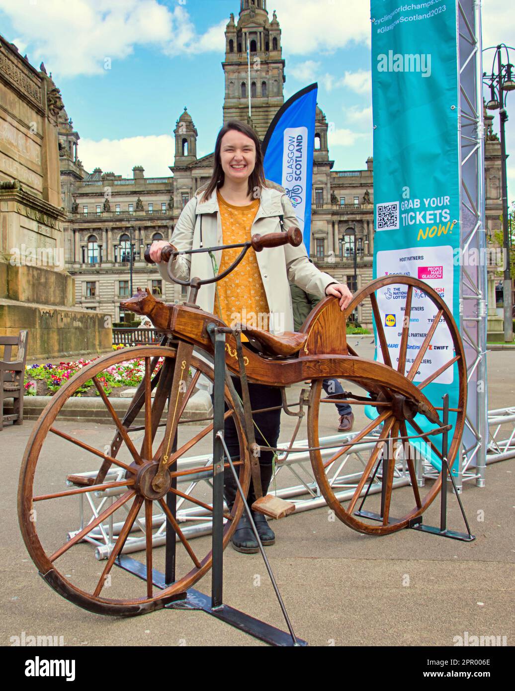 Glasgow, Scotland, UK 25th  April, 2023.  The 23 Million Mile Challenge in partnership with Love to Ride to mark 100 days to go until the inaugural cycling mega-event UCI ceremony memorial bike ride saw the commemoration of wooden bike route from Dumfries to Glasgow the first-ever bicycle ride undertaken by Scottish inventor Kirkpatrick Macmillan on the treadle bicycle in 1842.  in George square as the original journey was recreated featuring miss costello curator and a reproduction of the original bike from Dumfries museum. Credit Gerard Ferry Stock Photo