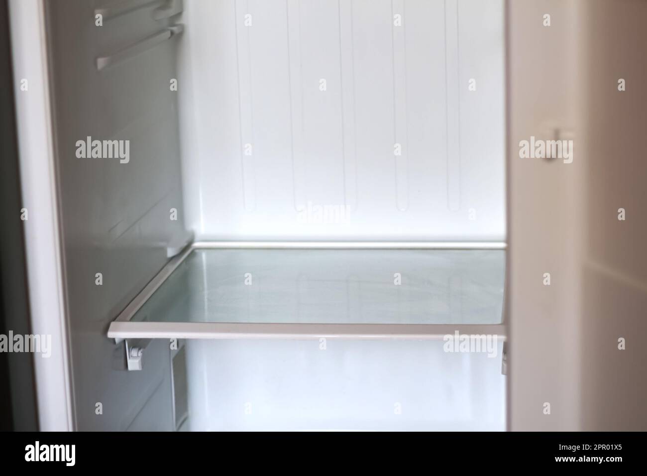 Empty open fridge with shelves, refrigerator. Inside of an empty white fridge. Out of focus Stock Photo
