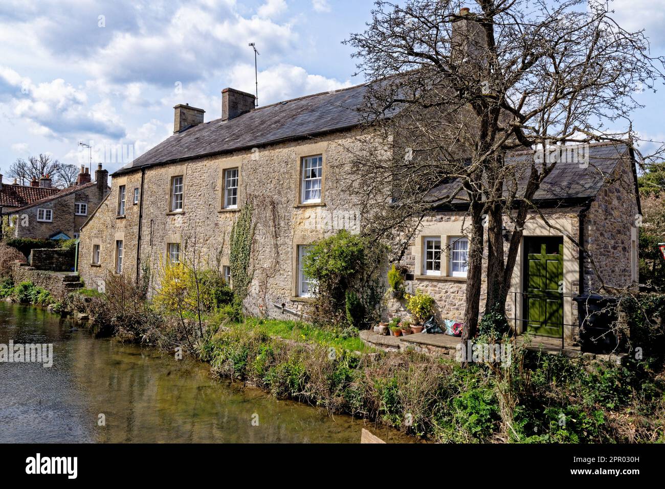 Pretty cottages and the Mells River at Nunney. Village of Nunney, Somerset, England, United Kingdom - 8th of April 2023 Stock Photo