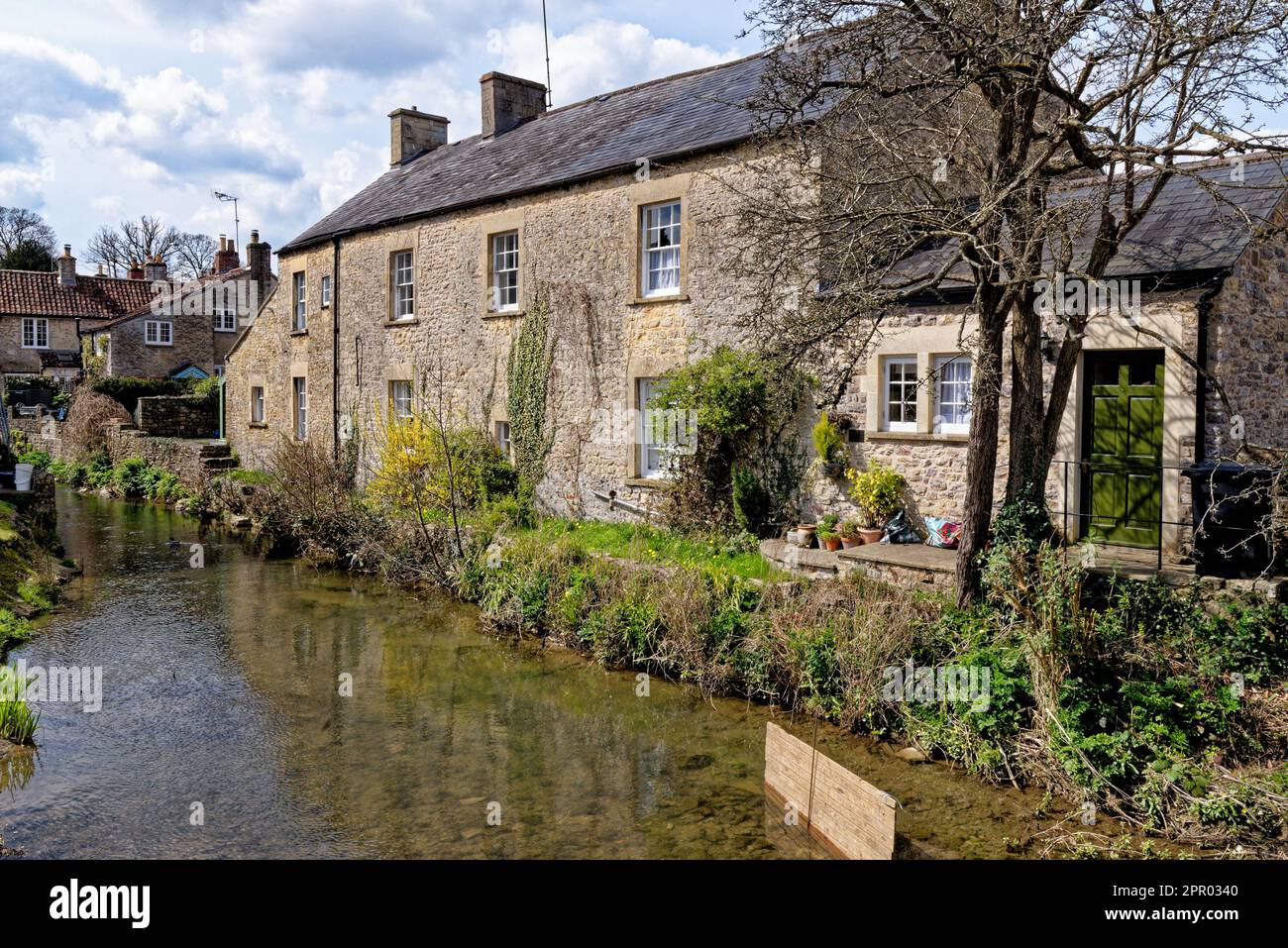 Pretty cottages and the Mells River at Nunney. Village of Nunney, Somerset, England, United Kingdom - 8th of April 2023 Stock Photo