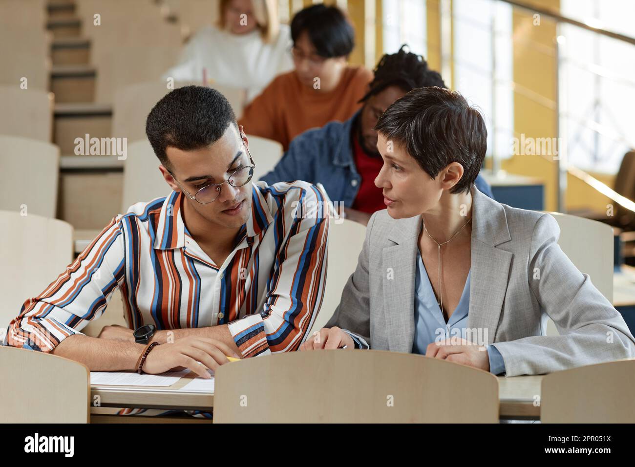 Mature teacher explaining new material to student while they sitting at ...