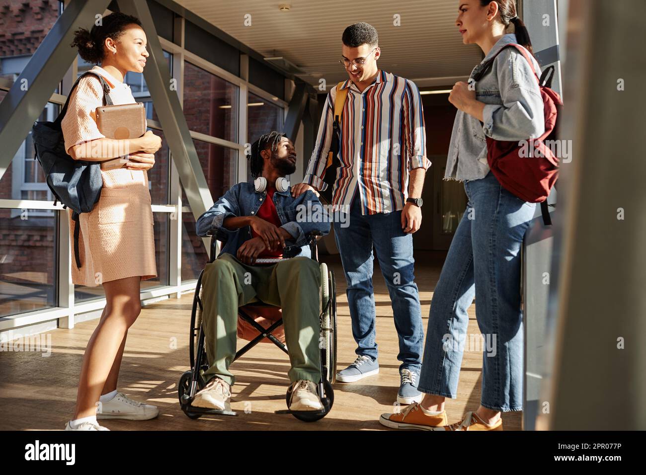 Student with disability sitting on wheelchair and talking to classmates ...
