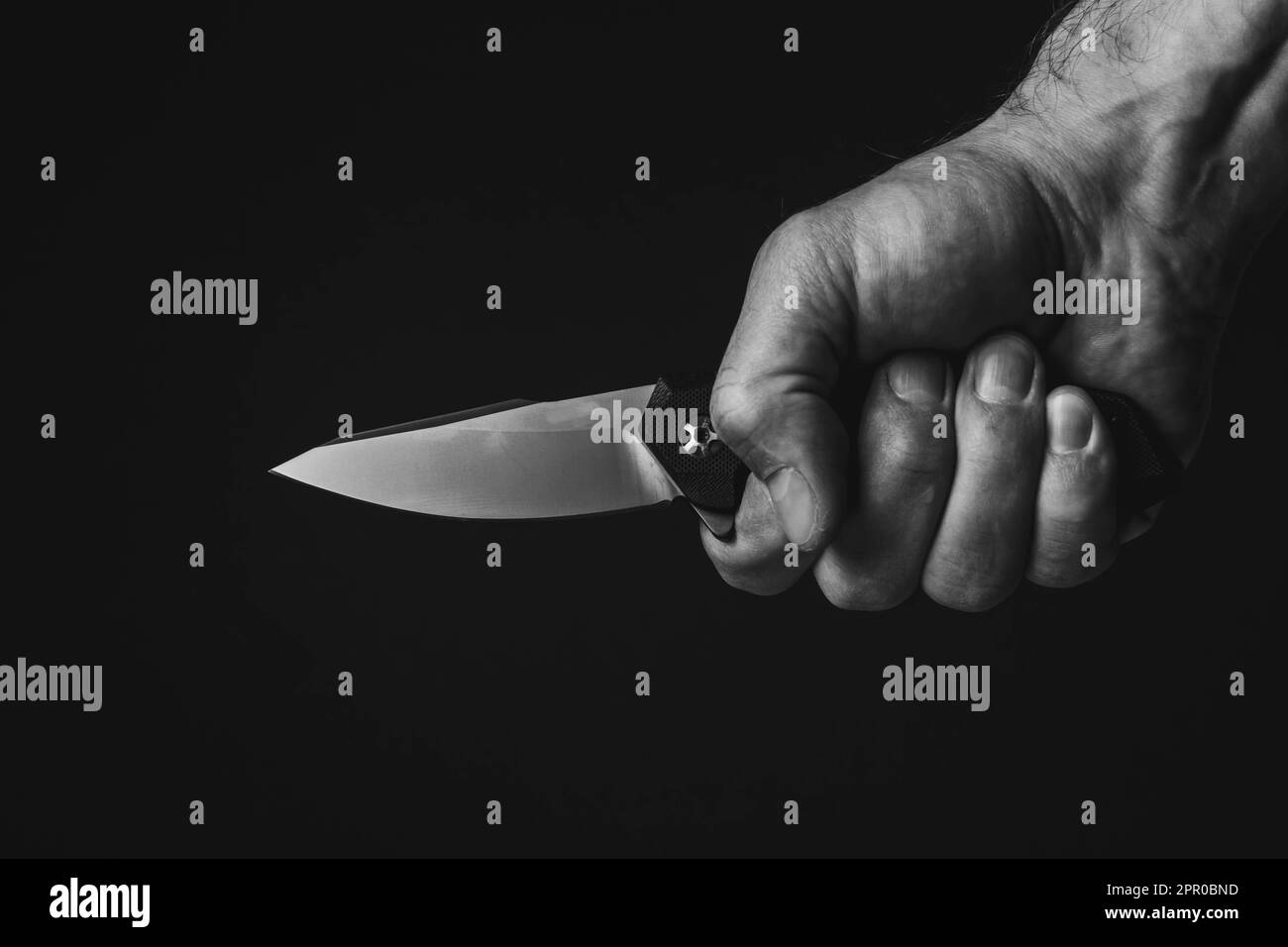 A sharp knife in the man's hand. The use of cold weapons. Knife attack . Armed raid.. Stock Photo