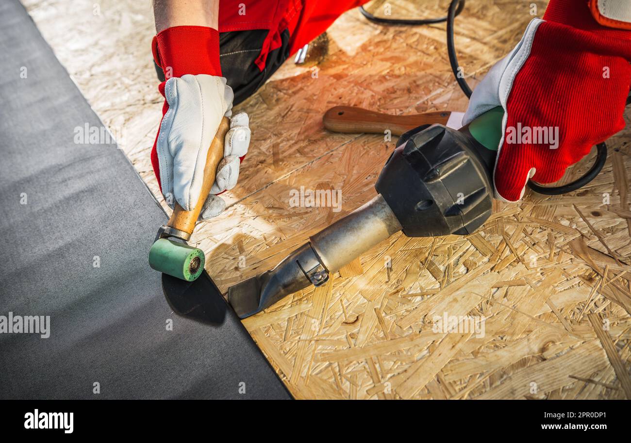 Caucasian Roofing Worker Installing EPDM Membrane Material Using Hot