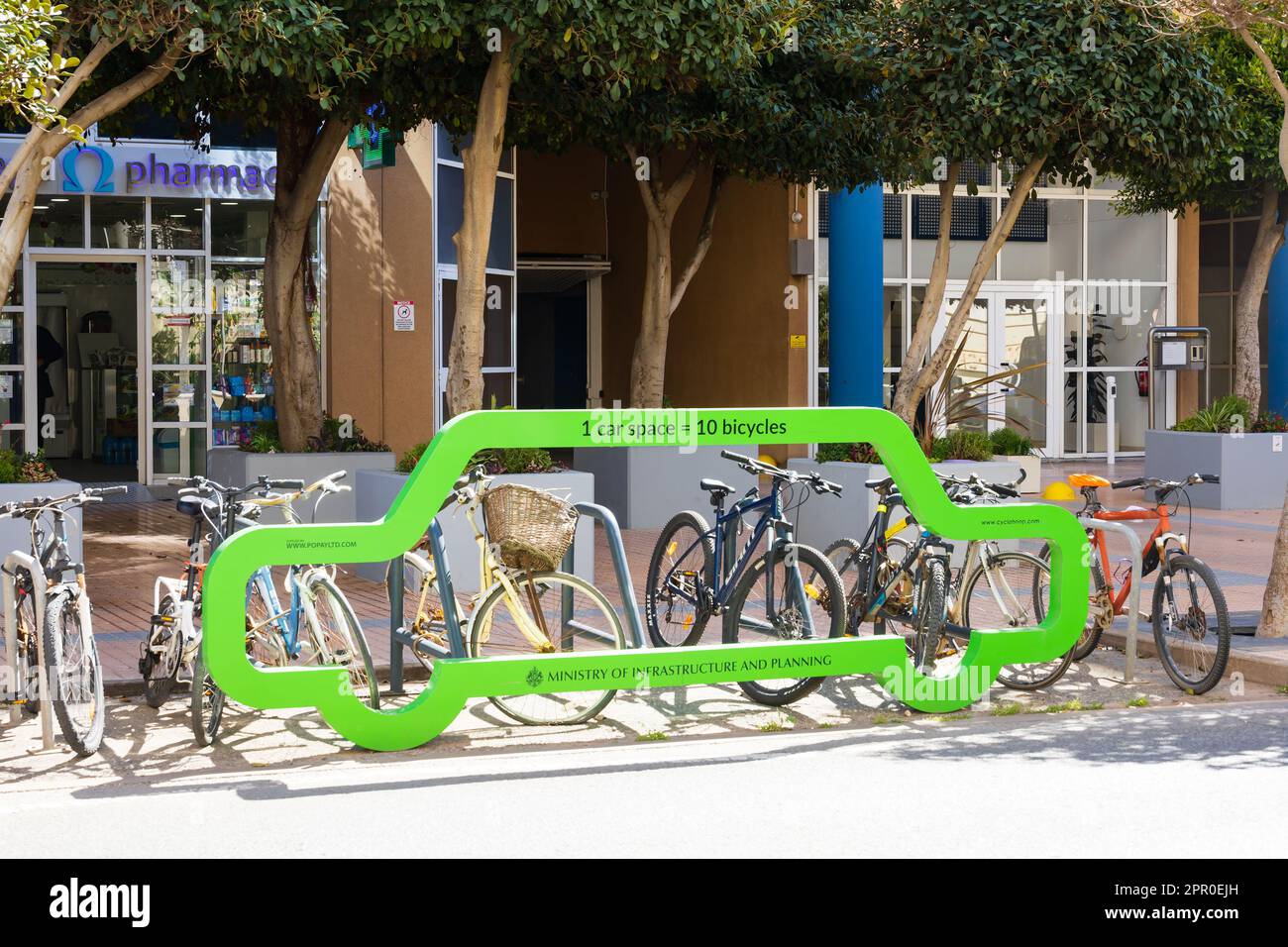 Bright green bike rack demonstrating the space taken by a car instead of 10 bicycles. The British Overseas Territory of Gibraltar, the Rock of Gibralt Stock Photo