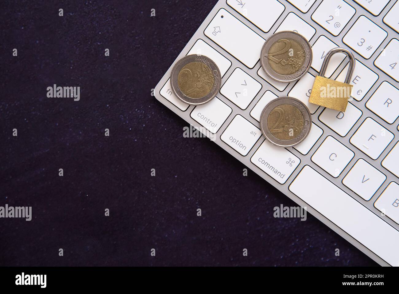 Closed padlock on some euro coins on a laptop frame. Keep our savings safe. Space for copy text. Dark background. Stock Photo