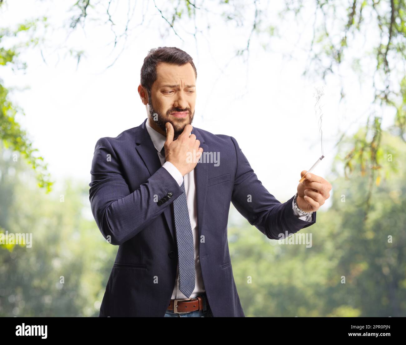 Doubtful man holding a cigarette in a park Stock Photo