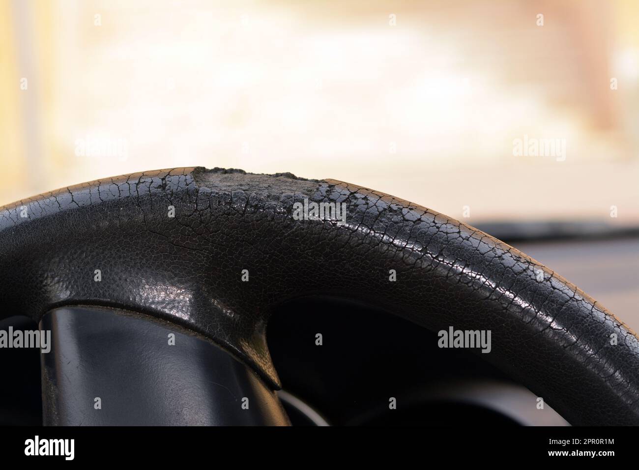 cracks and damaged rubber of the car steering wheel due to long exposure to the sunlight, substandard materials in the manufacture of automotive parts Stock Photo