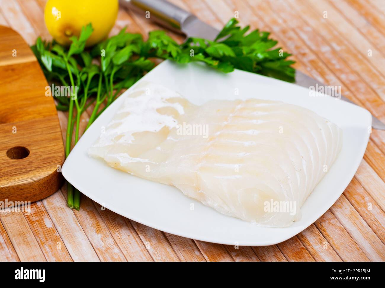 Fresh raw kingklip fillet with greens, lemon and spices Stock Photo
