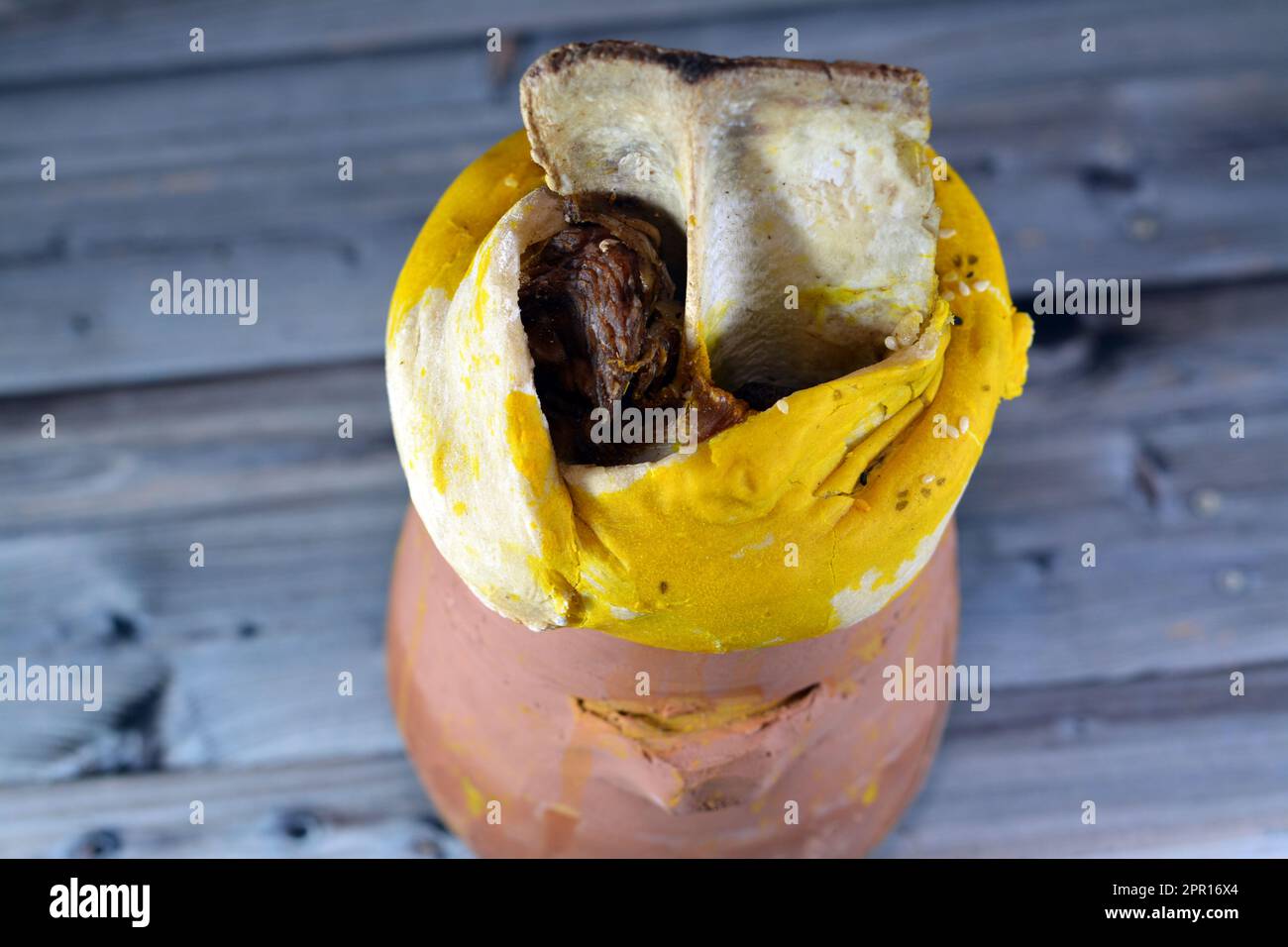 A pottery hot pot Jar covered with dough, sesame and lamb shank is inside it with Basmati rice and mixed vegetables and stuffed grape leaves mahshi Ma Stock Photo
