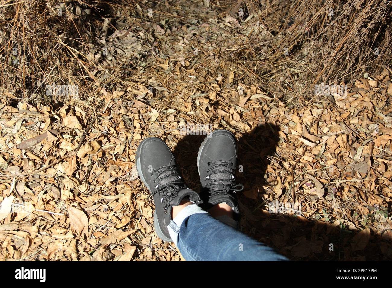 Legs of a woman with denim pants and black hiking boots walking alone