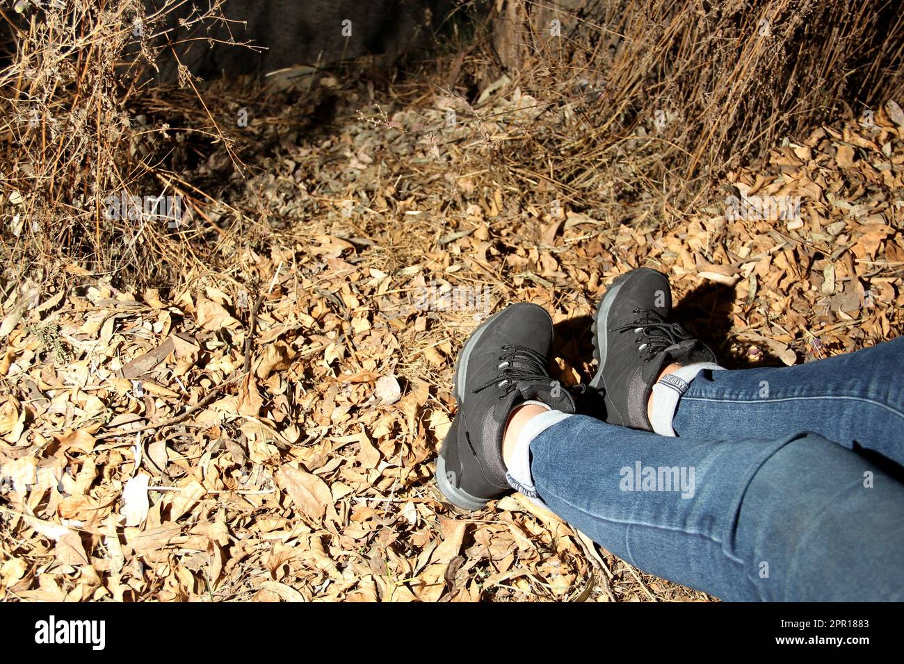 Legs of a woman with denim pants and black hiking boots walking alone