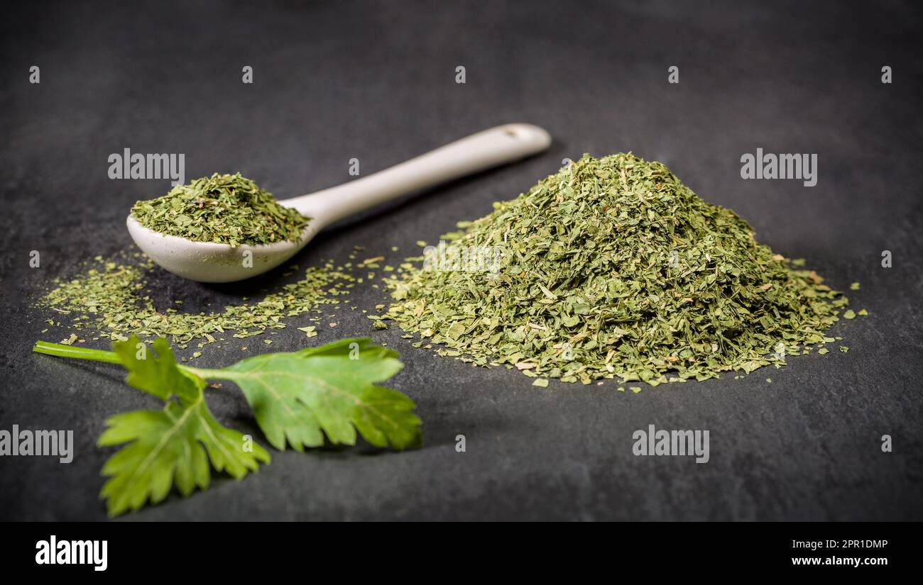 Spices for recipes. Parsley. A spoon and a pile of ground dried parsley spice. Recipe ingredients. Stock Photo