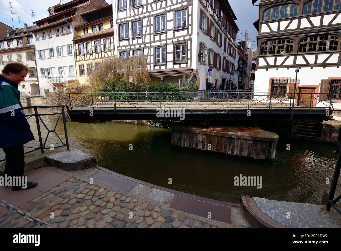 People wait to cross Pont du Faisan while in the open position. The bridge is a hydraulic, or swing bridge over the Ill River in Strasbourg, France. Stock Photo